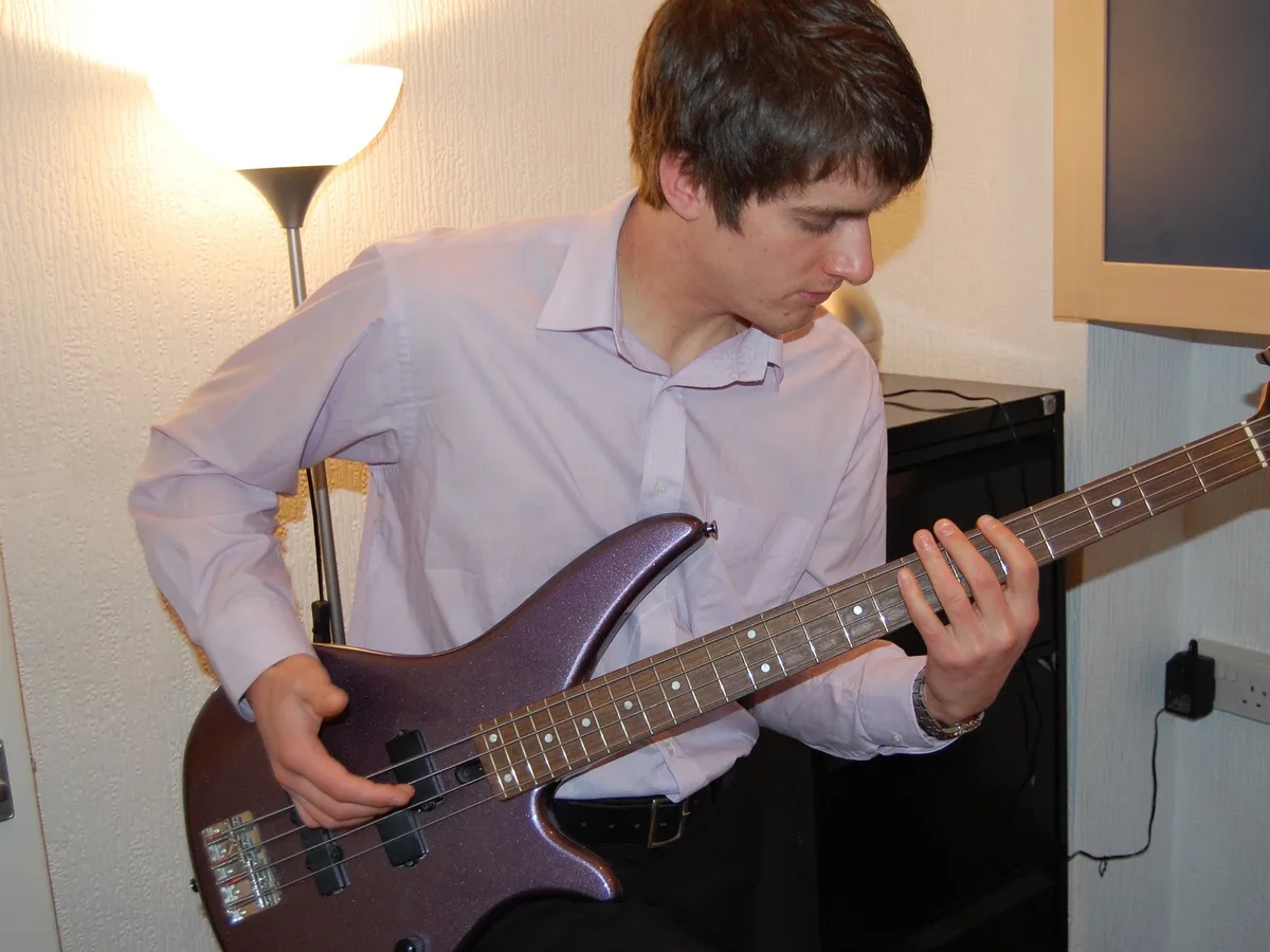 A student playing bass guitar at the Rīgas Privātā Mūzikas Skola studio in Riga
