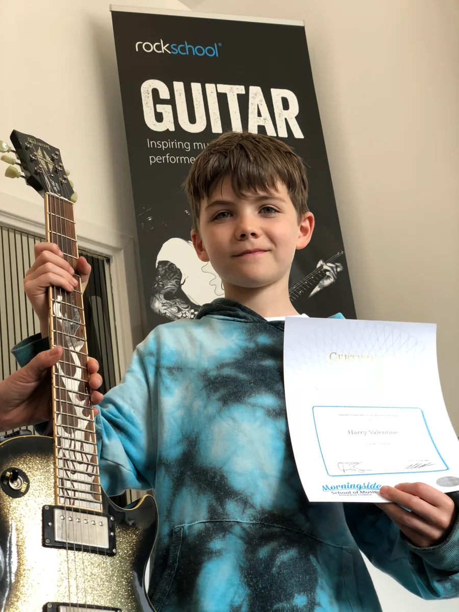 A young guitar student with his certificate at Rīgas Privātā Mūzikas Skola in Riga